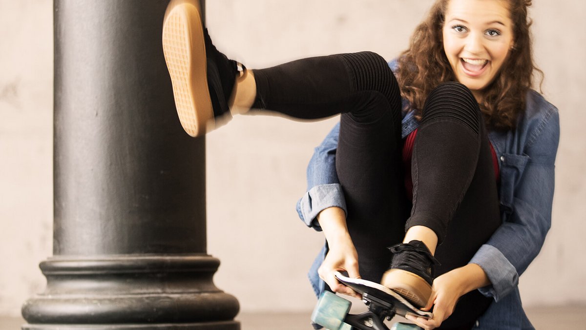 Junge Frau sitzt auf Skateboard OVB