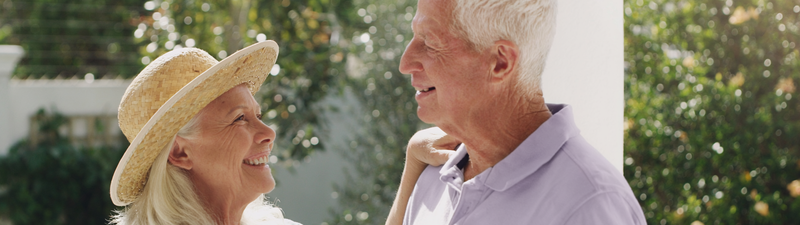 Älteres Paar lächelt sich im Garten liebevoll an.