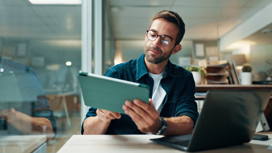 Finanzberater am Arbeitsplatz mit einem Tablet in der Hand