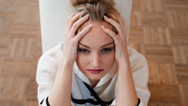 Anzeichen, dass Sie einen Digital Detox benötigen Frau stützt gestresst den Kopf auf die Hände