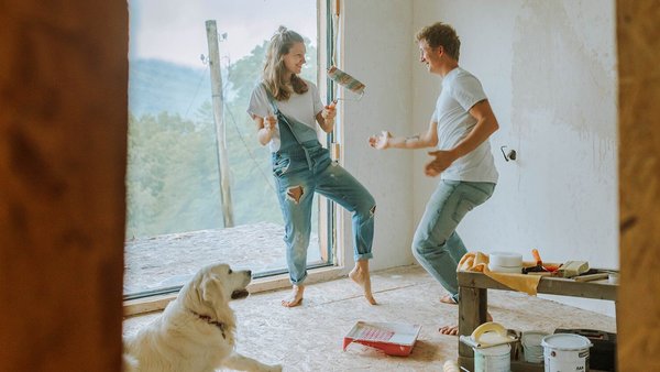 Pärchen tanzt mit Hund zusammen im neuen Haus – Baufinanzierung Pärchen tanzt mit Hund zusammen im neuen Haus – Baufinanzierung