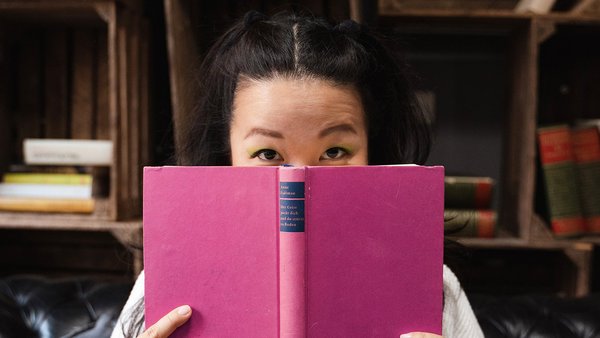 Schritt 3: Freie Zeiten nutzen und Alternativen schaffen Junge Frau hält ein Buch vors Gesicht