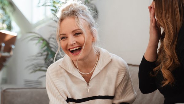 Lachende Frau mit Kollegin motiviert sich selbst bei der Arbeit