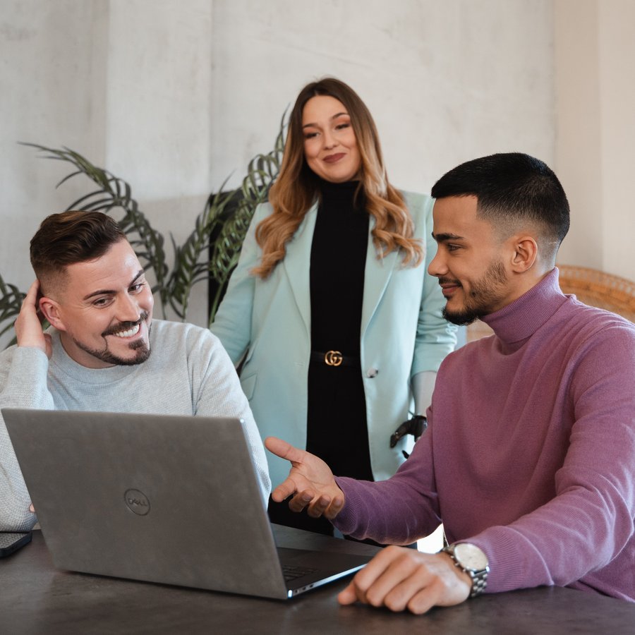 Drei Personen besprechen gemeinsam etwas am Laptop.