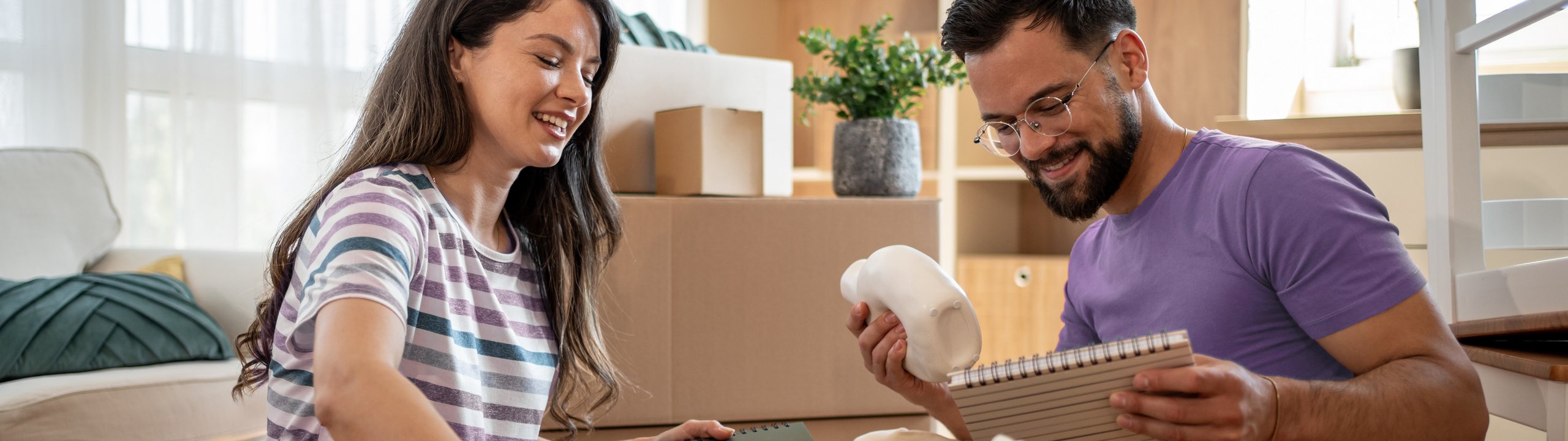 Paar packt Umzugskartons in einer neuen Wohnung aus.