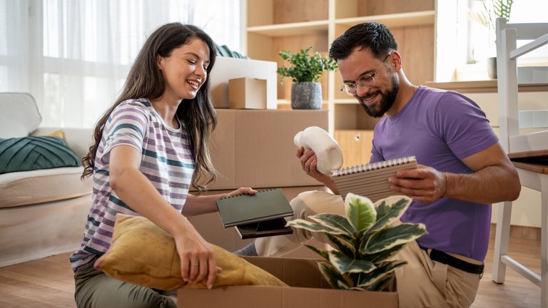 Paar packt Umzugskartons in einer neuen Wohnung aus.