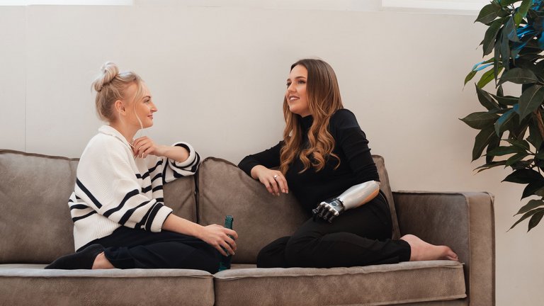 Zwei Frauen sitzen entspannt auf einem Sofa und unterhalten sich.