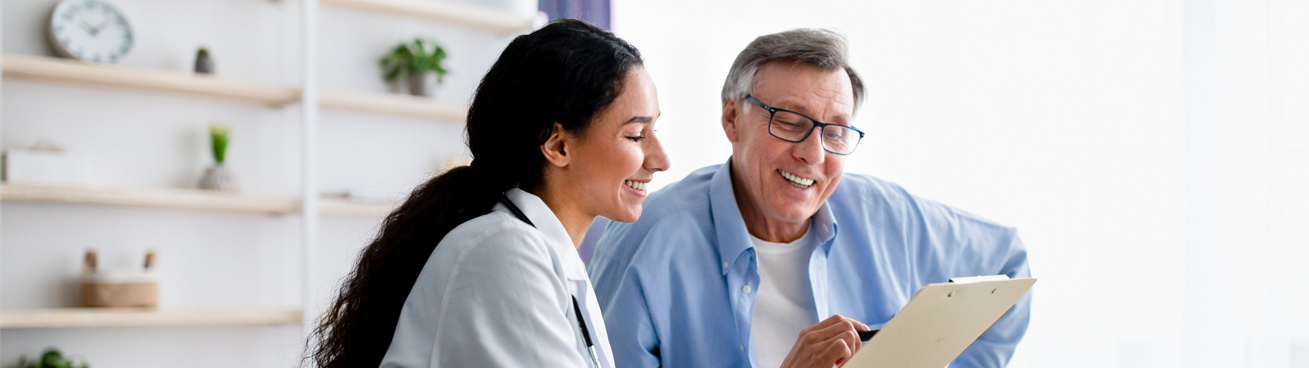 Ärztin erklärt einem älteren Mann etwas auf einem Tablet.