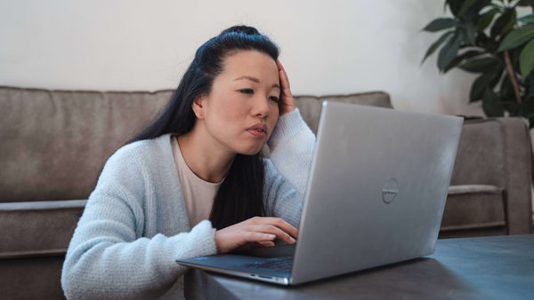 Eine Frau sitzt besorgt an ihrem Laptop 