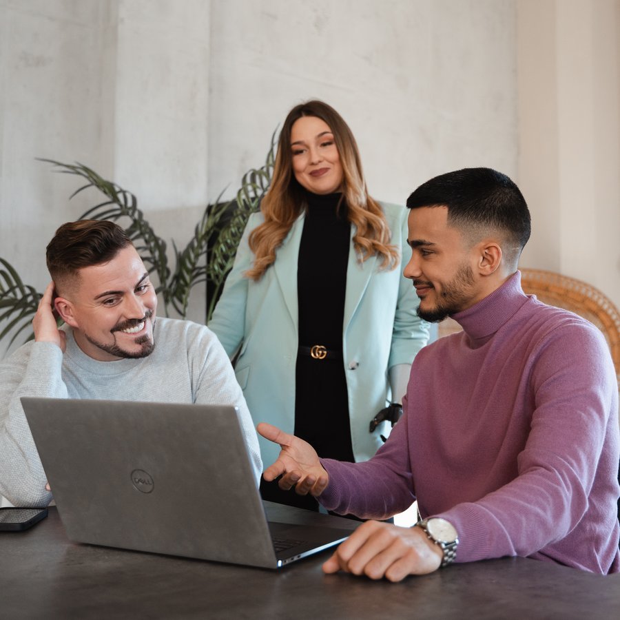 Drei Personen besprechen gemeinsam etwas am Laptop.