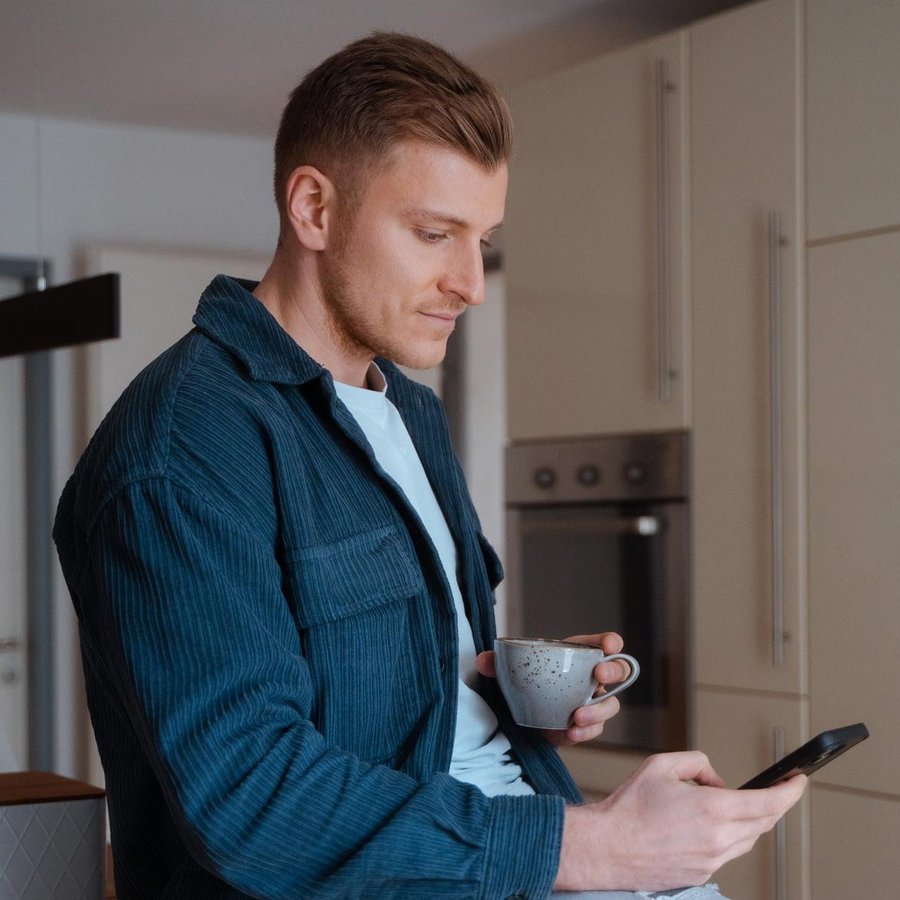 Mann sitz in der Küche und schauts auf sein Handy Mann sitz in der Küche und schauts auf sein Handy