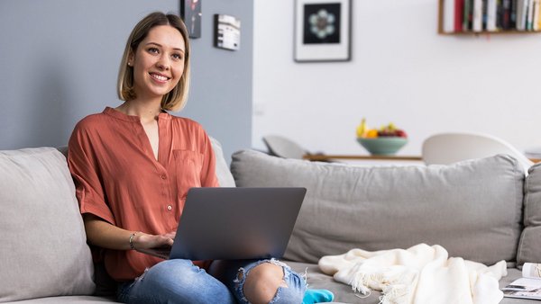 Frau mit Laptop auf der Couch – Work-Life-Integration Frau mit Laptop auf der Couch – Work-Life-Integration