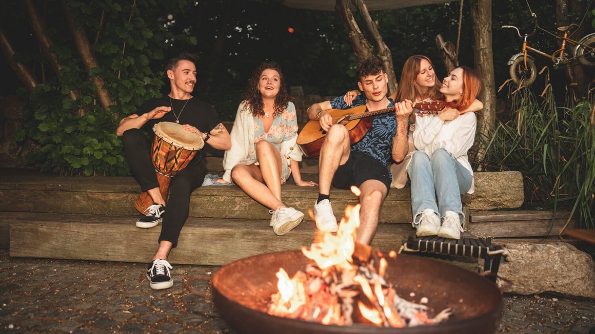 Junge Leute sitzen am Lagerfeuer – Abenteuer Vanlife