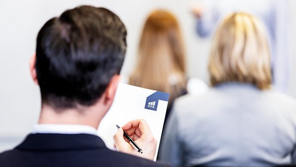 Was genau ist berufliche Weiterbildung? Mitarbeiter in einer beruflichen Fortbildung macht sich Notizen