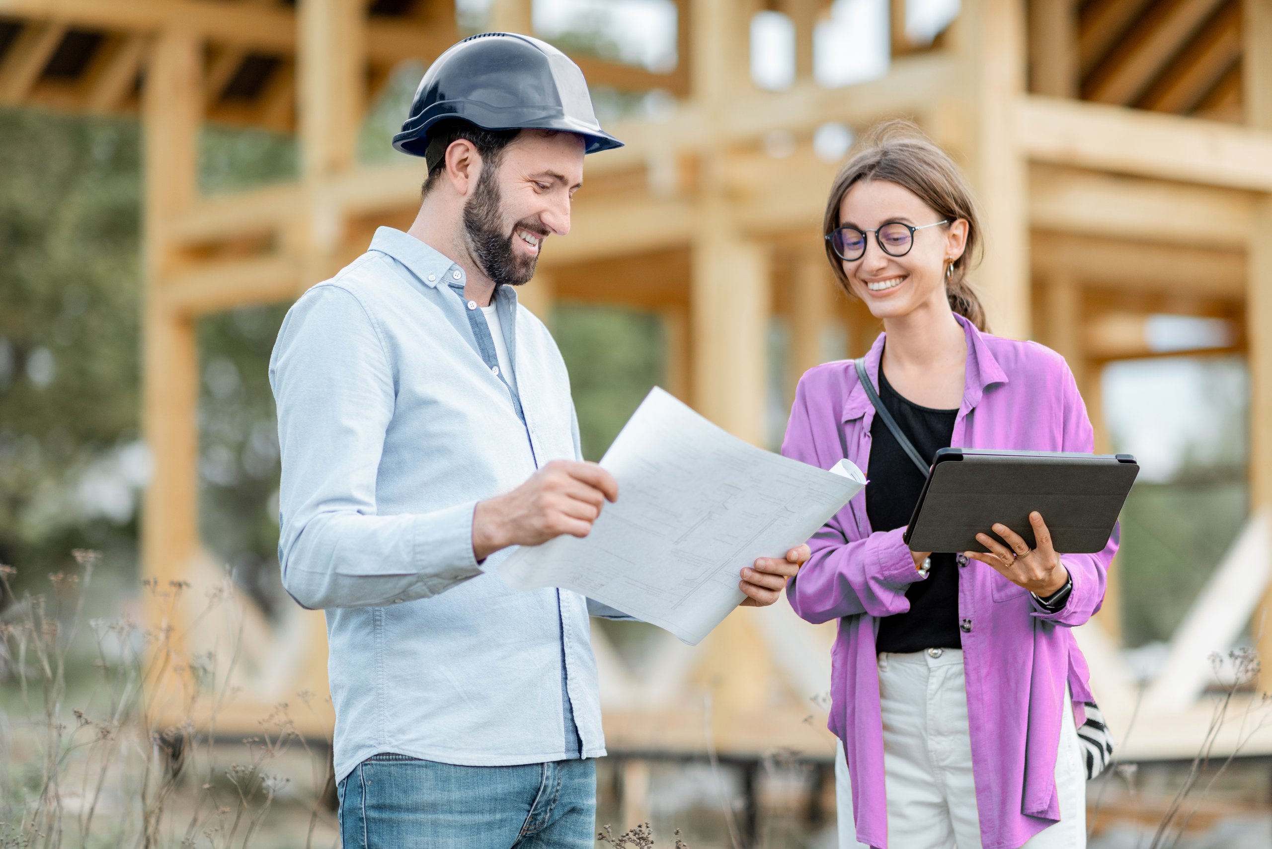 Zwei Fachkräfte prüfen Baupläne auf einer Baustelle.