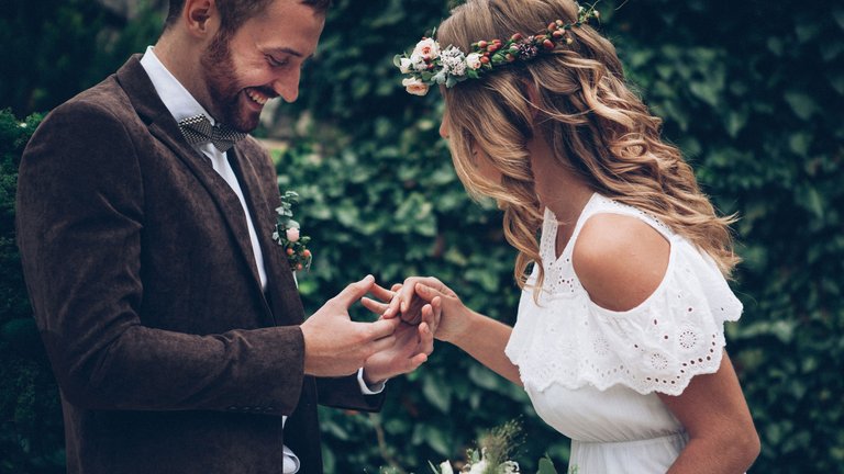 Brautpaar betrachtet bei ihrer Hochzeit die Ringe an ihrer Hand.