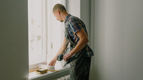 Mann repariert ein Fenster - private Berufsunfähigkeitsversicherung
