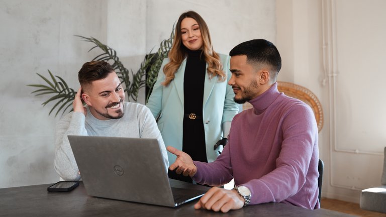 Drei Personen besprechen gemeinsam etwas am Laptop.