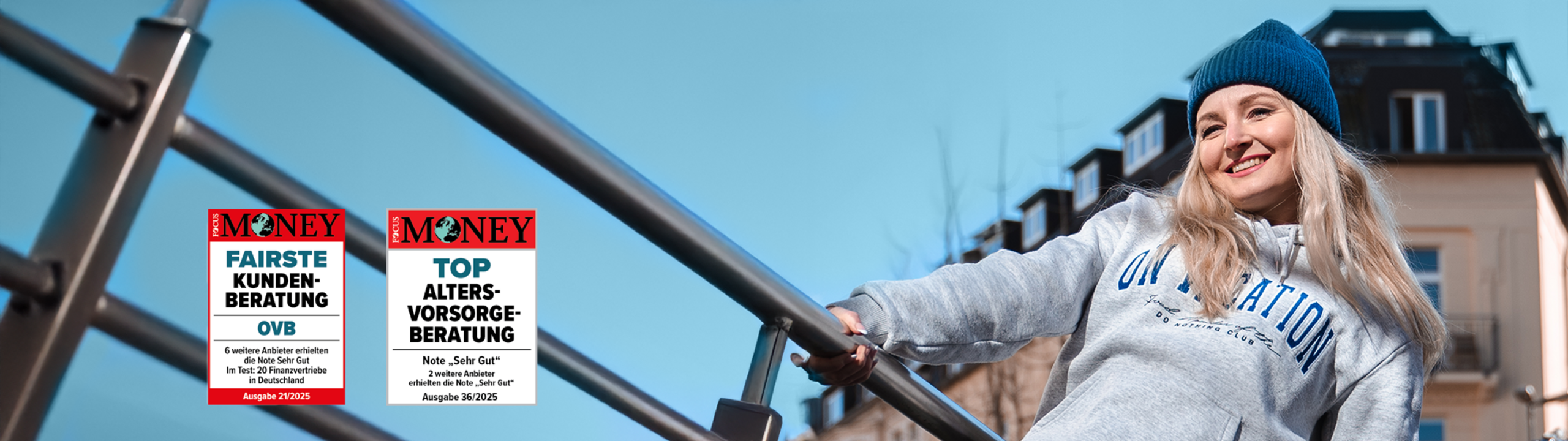 Blonde Frau mit blauer Mütze hält sich am Geländer fest