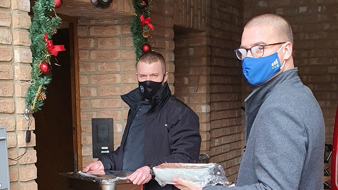 2 Mitarbeiter der OVB Regionaldirektion Ahrweiler stehen vor Haustür mit Gesichtsmaske um Essen an Weihnachten zu liefern