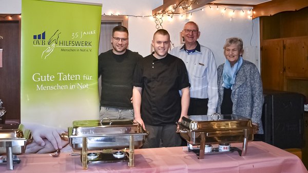 Weihnachtsbuffet für Bedürftige. 3 Chafing-Dishs im Vordergrund auf Tisch, 4 Menschen im Hintergrund.