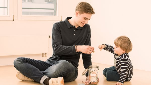Kind und junger Mann sparen Geld in einem Glas