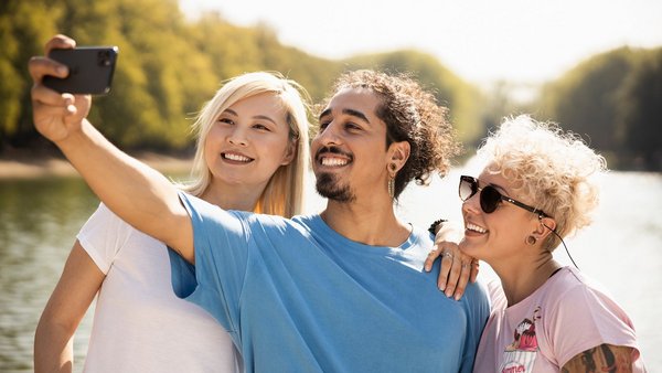 Drei junge Menschen machen ein Selfie im Park