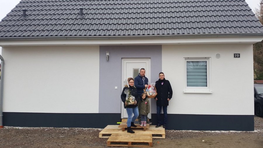Familie K mit OVB Berater Baumgart vor dem Eigenheim