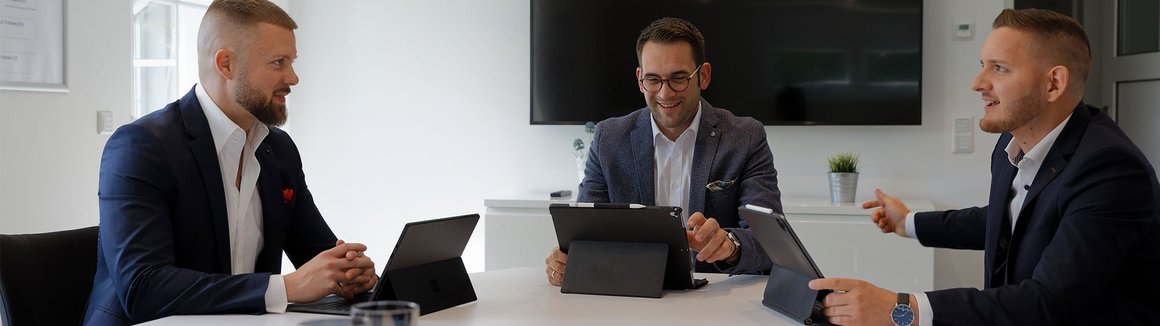 drei Berater aus dem Teasm Bickert sitzen am Tisch im Bepsrechungsraum