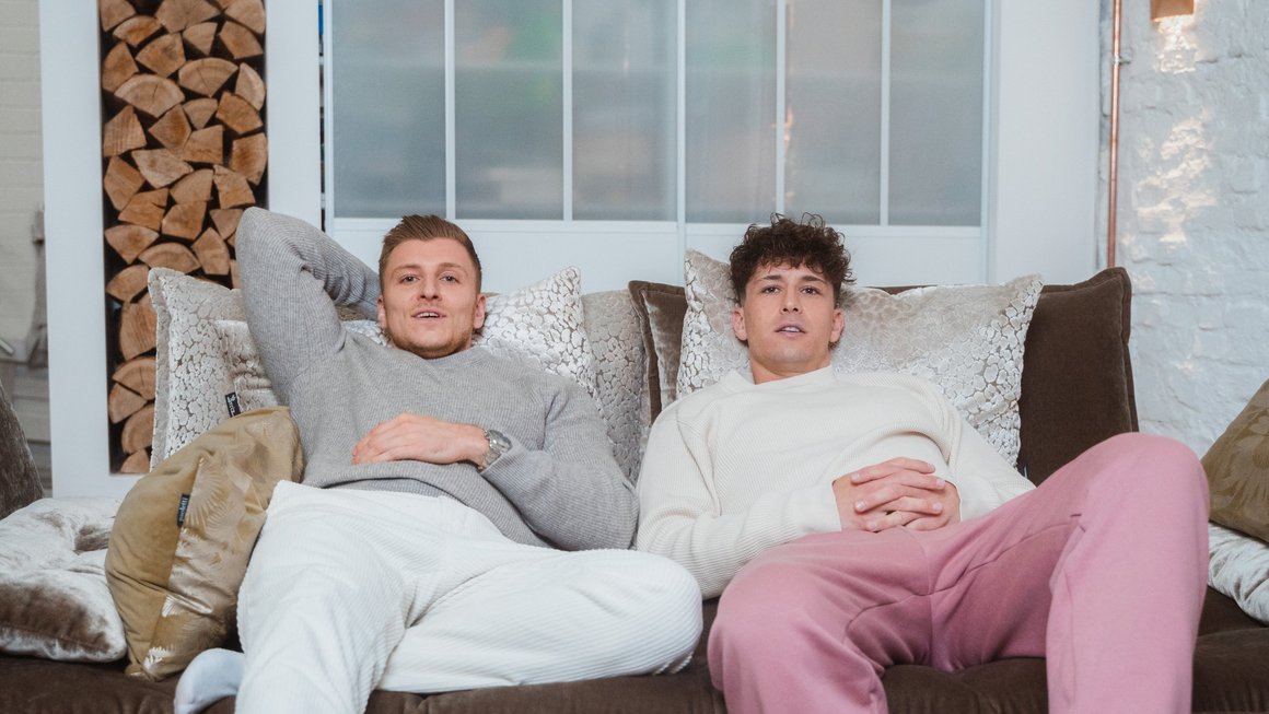Zwei Männer sitzen auf dem Sofa.