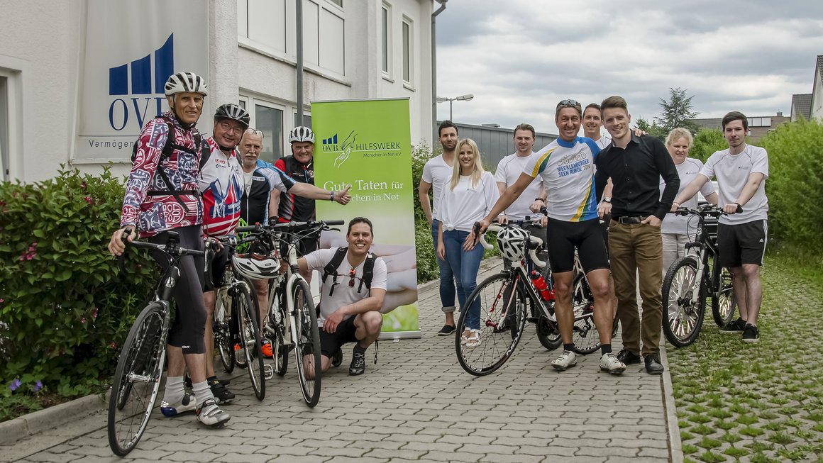 13 Radfahrer mit Helm und Rad vor OVB Büro in Bayreuth
