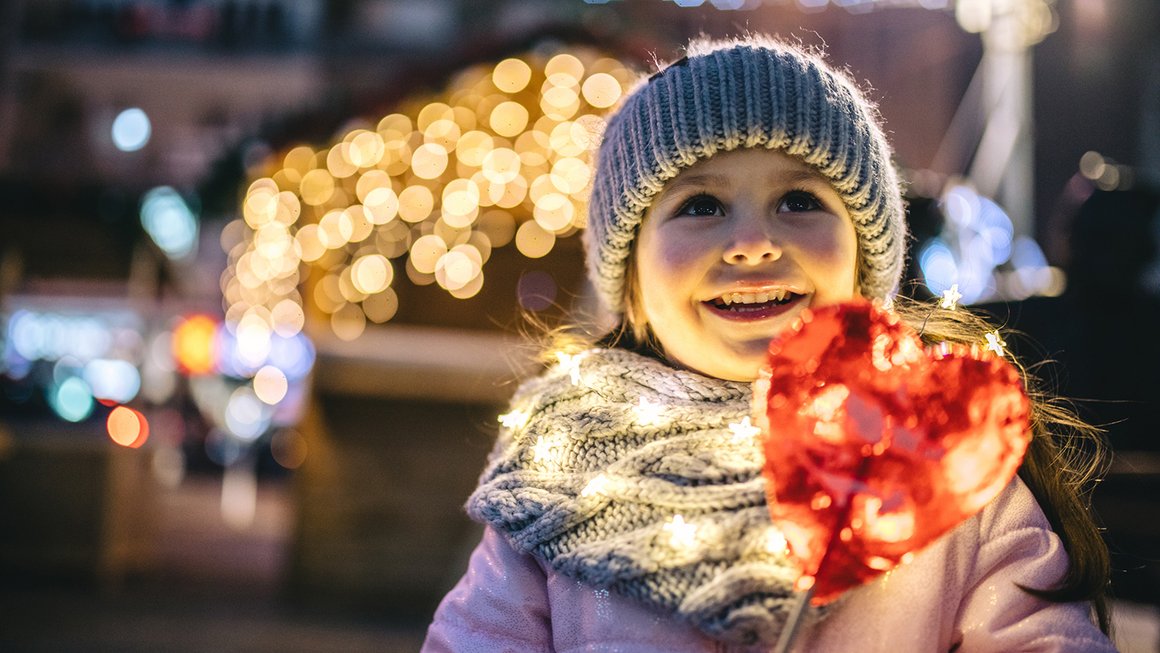 Mädchen mit Herz und Weihnachtslichtern – Geld richtig anlegen