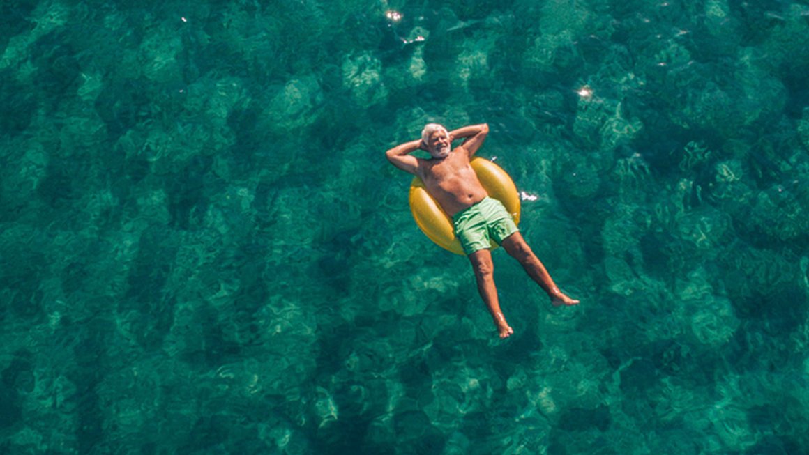 Altersvorsorge: Rentner entspannt mit Schwimmreifen auf dem Wasser