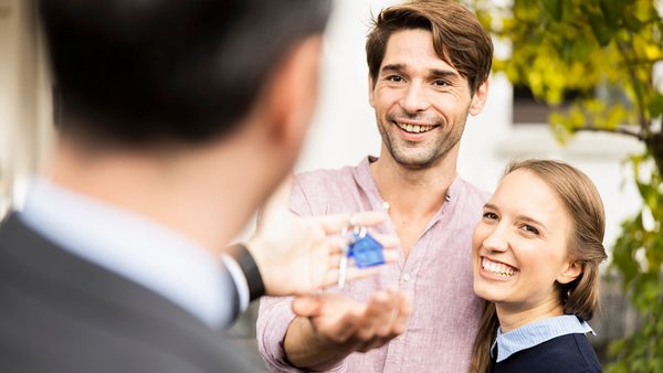 Junges Paar erhält Hausschlüssel nach Bausparen Junges Paar erhält Hausschlüssel nach Bausparen