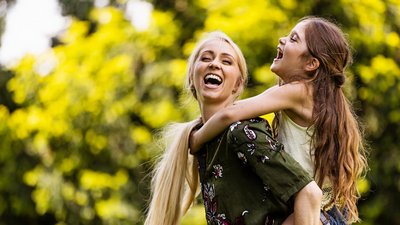 Junge Frau mit Mädchen auf dem Rücken OVB