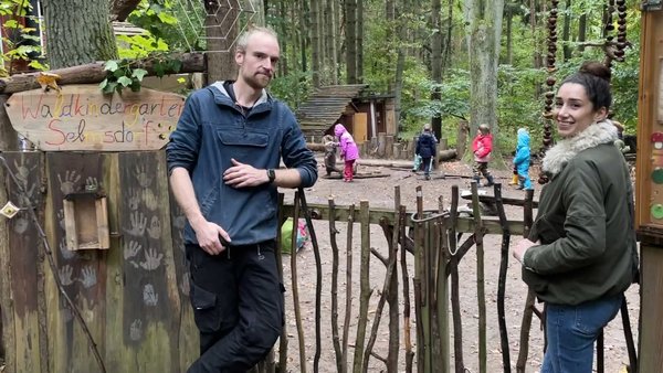 Sevcan Ehmke steht mit Betreuer des Waldkindergartens Selmdorf im Wald am Zaun