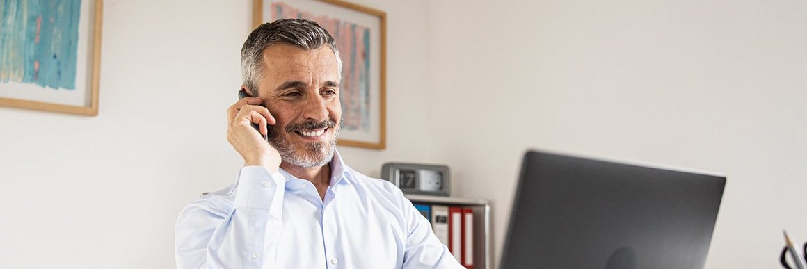 Zufriedener Mann mit Telefon und Laptop