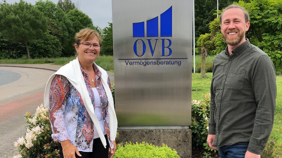 OVB Schild in der Mitte. Frau links mit Brille, Mann rechts mit Bart