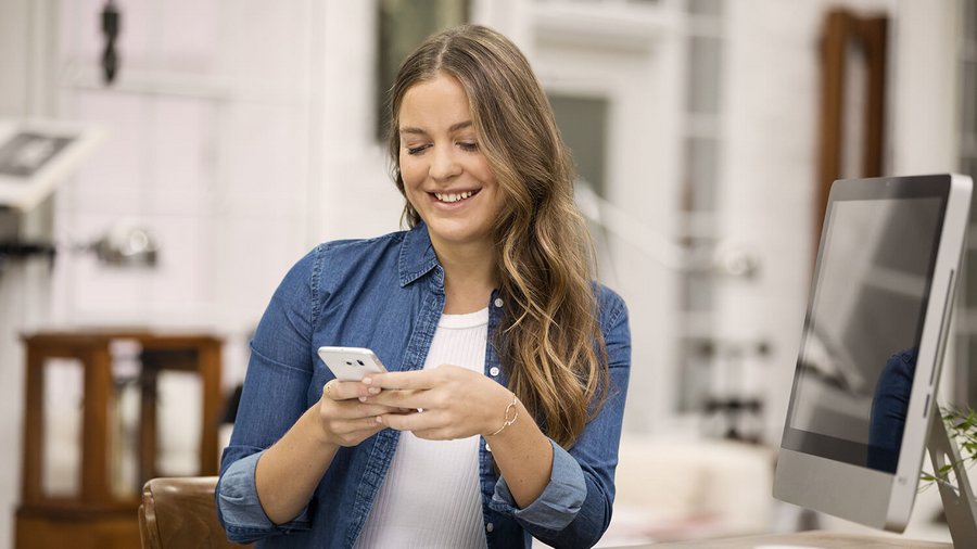 Lächelnde Frau mit Smartphone OVB Hilfswerk