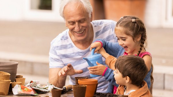 Großvater und Enkelkinder pflanzen Blumen