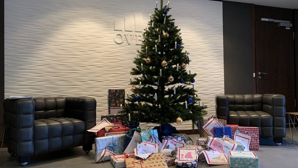 Geschmückter Weihnachtsbaum im Foyer der OVB Zentrale am Kölner Heumarkt. Vor dem Weihnachtsbaum liegen viele eingepackte Geschenke