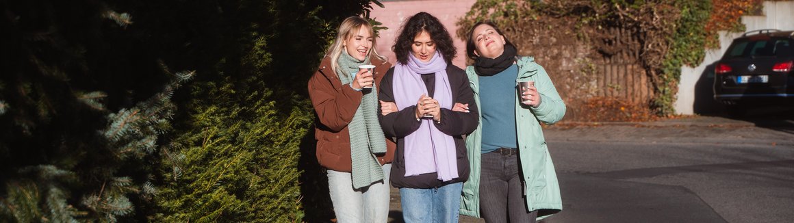 drei Frauen nebeneinander auf dem Gehweg
