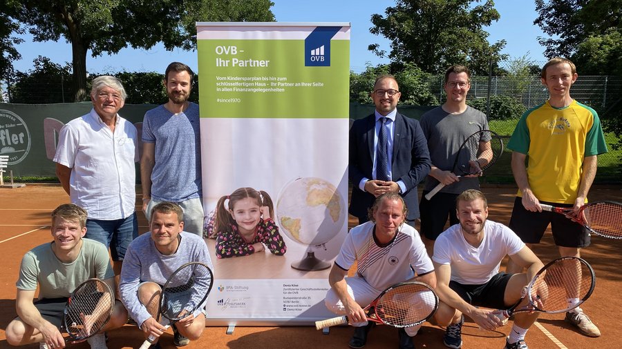 Deniz Köse und sein Team bei der sozialen Initiative des TC Bierstadt Tennisclubs. 9 Männer mit Tennisschläger auf dem Tennisplatz.
