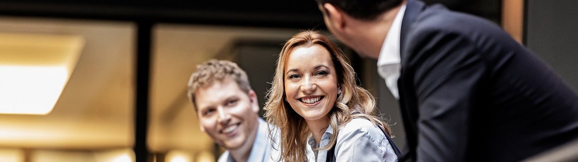 drei Personen lehnen lächelnd am Geländer an