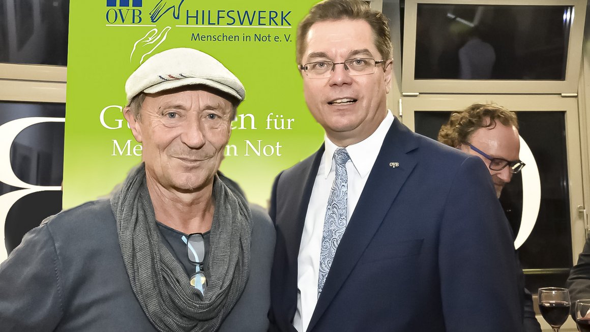 Der Leiter der Bahnhofsmission am Berliner Zoo Dieter Puhl steht mit Kappe auf links. Rechts steht Rolf Butschkat, Landesdirektor für die OVB Vermögensberatung AG in Berlin, im dunklen Anzug und Krawatte