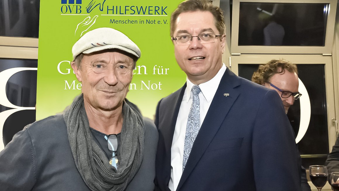 Der Leiter der Bahnhofsmission am Berliner Zoo Dieter Puhl steht mit Kappe auf links. Rechts steht Rolf Butschkat, Landesdirektor für die OVB Vermögensberatung AG in Berlin, im dunklen Anzug und Krawatte 