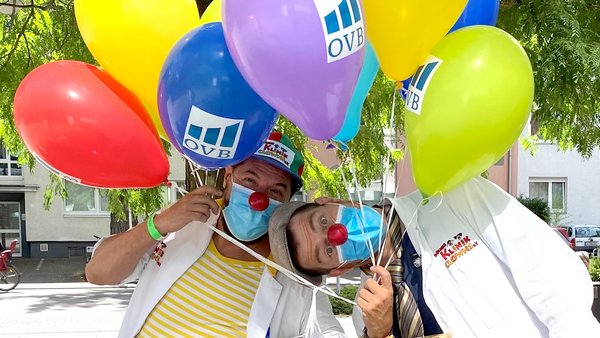 Zwei Klinikclowns mit vielen bunten Ballons mit OVB Logo darauf