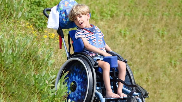 Matteo Joedecke im Rollstuhl auf Wiese im Sommer