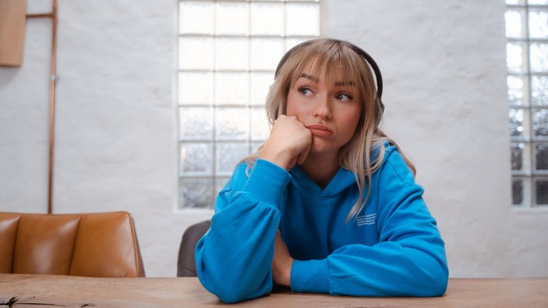 Frau mit blonden Haaren schaut nachdenklich.
