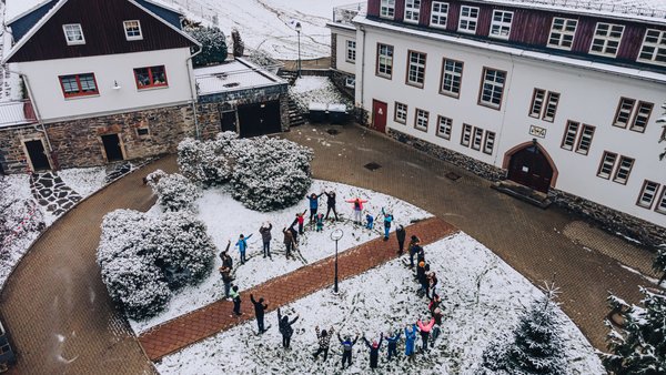 Kinder- und Jugendwohnen Tannenmühle aus der Vogelperspektive. Bewohner formen im Hof ein großes Herz als Menschenkette.